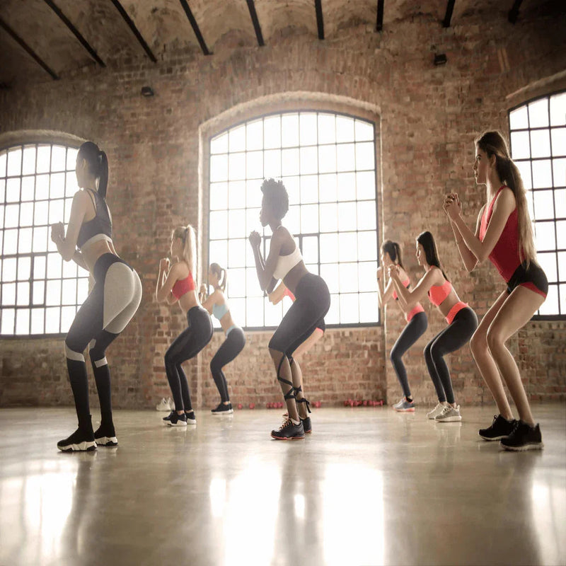 group of women doing squat exercises together indoors