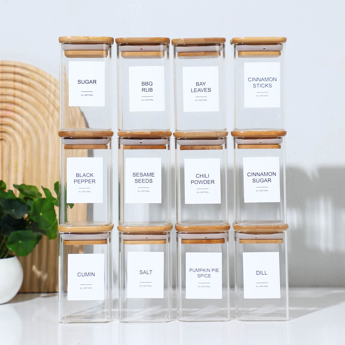 12 square glass spice jars with bamboo lids and printed labels displayed together