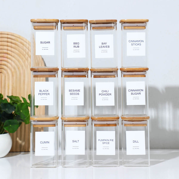 12 square glass spice jars with bamboo lids and printed labels displayed together