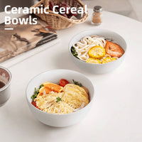 Two white speckled ceramic bowls on white table filled with udon soup and mixed rice bowl