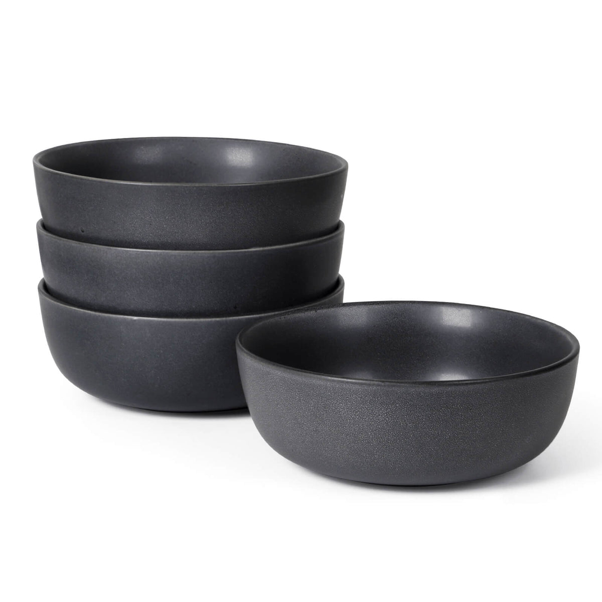 Four charcoal dark grey matte ceramic bowls stacked on white background, one bowl placed separately in front