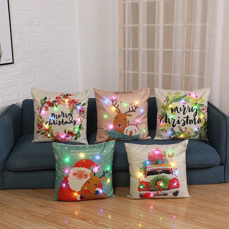 Five Christmas-themed decorative pillows with festive lights on a blue sofa and wooden floor