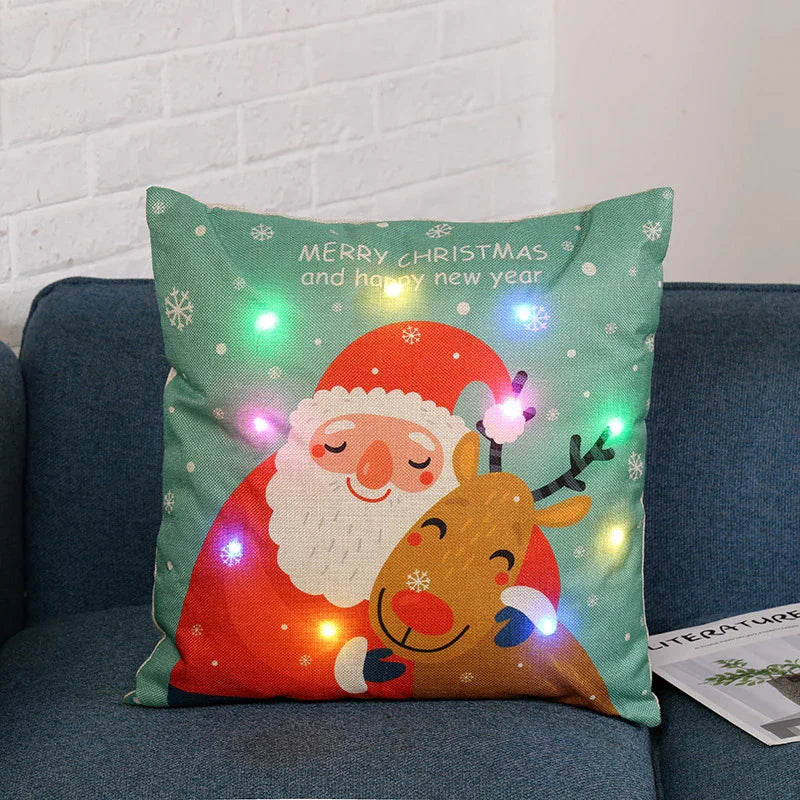 Christmas pillow with Santa and reindeer illustration, decorative LED lights, green background on blue sofa