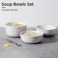 Four white speckled ceramic bowls on grey surface, two filled with noodle soup and oatmeal