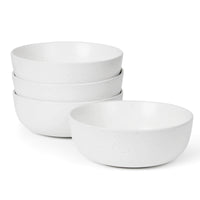 Four white speckled matte ceramic bowls stacked on white background, one bowl placed separately in front