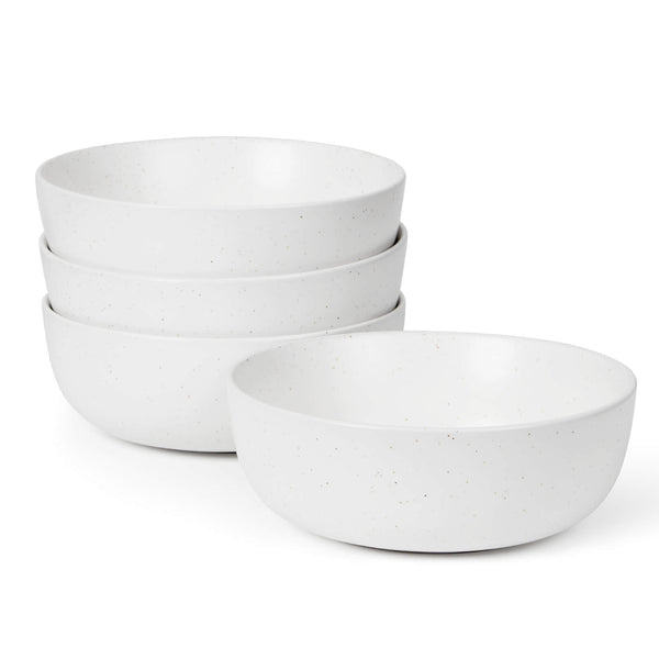 Four white speckled matte ceramic bowls stacked on white background, one bowl placed separately in front