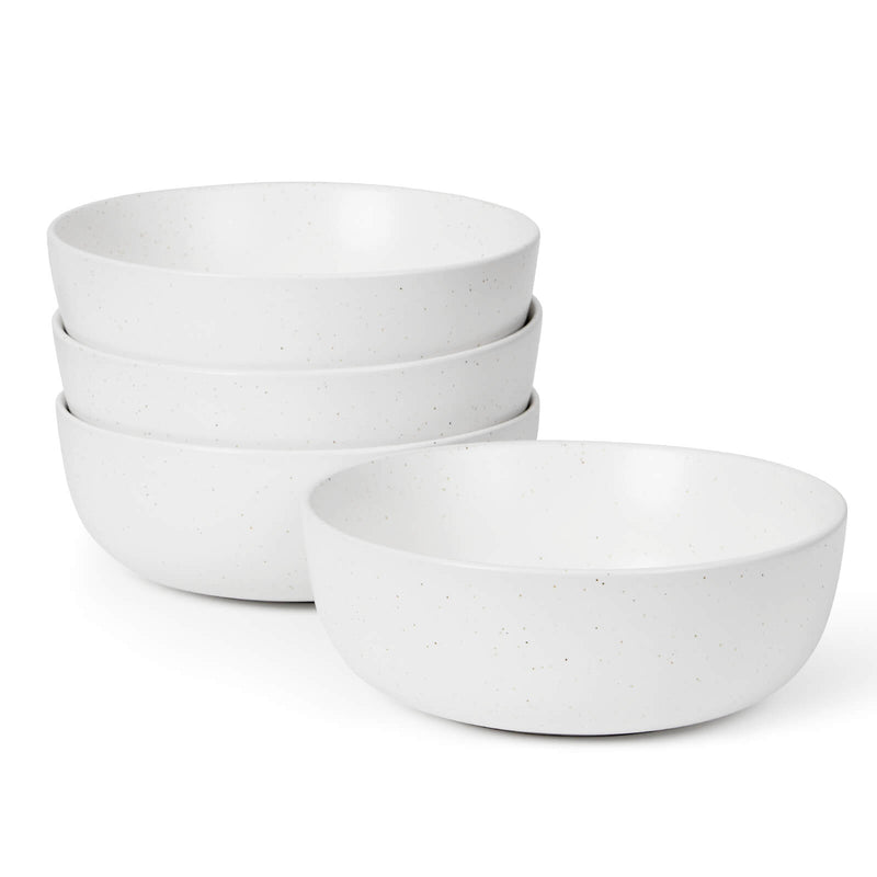 Four white speckled matte ceramic bowls stacked on white background, one bowl placed separately in front