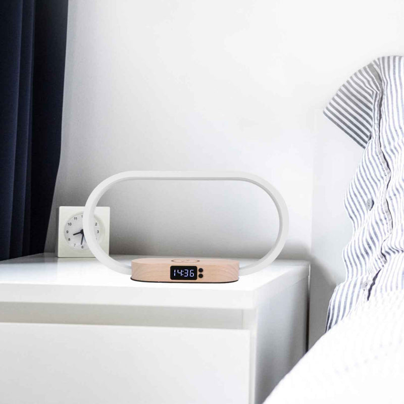 Minimalist bedside touch lamp with wireless charging pad and digital clock placed on white nightstand beside bed