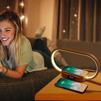 Woman relaxing on bed beside minimalist wooden bedside lamp with wireless charging station and digital clock on nightstand