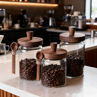 Glass storage jars with wooden lids displayed on kitchen counter in warm restaurant setting