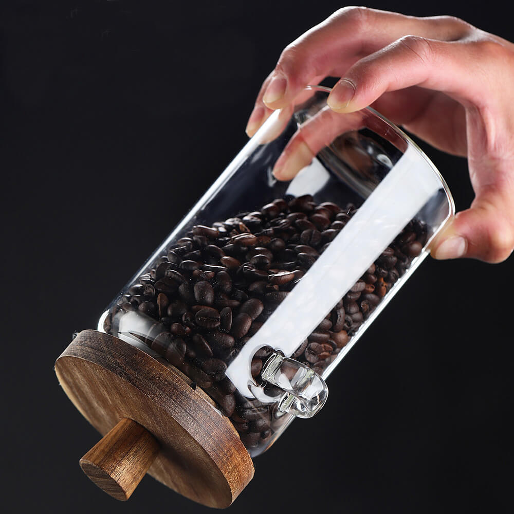 Hand opening glass storage jar with natural wooden lid to access contents