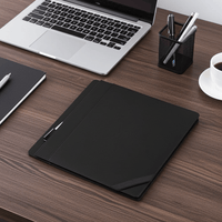 Black leather portfolio folder with pen detail on wooden desk beside laptop and pen holder