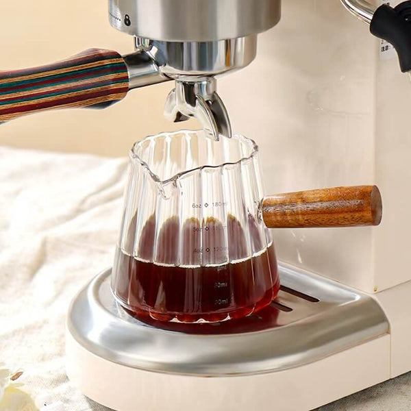 Mini borosilicate glass coffee cup with natural wooden handle on warm wooden surface