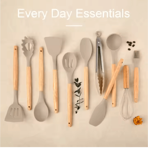 Silicone cooking utensils with wooden handles arranged flat lay styled with greenery